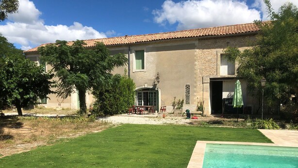 Una casa amb piscina, gespa i zona de pati.