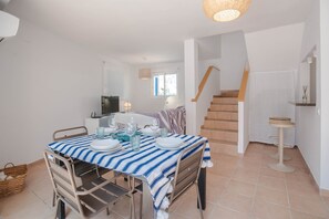 A dining area with a striped tablecloth, a TV, and a staircase leading to another level.