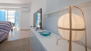 Una habitación de hotel moderna con una cama grande, un televisor de pantalla plana, una mesa de centro de vidrio y una lámpara esférica original.