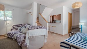 Un dormitorio moderno con cama, sofá, mesa de comedor y zona de cocina con taburetes.