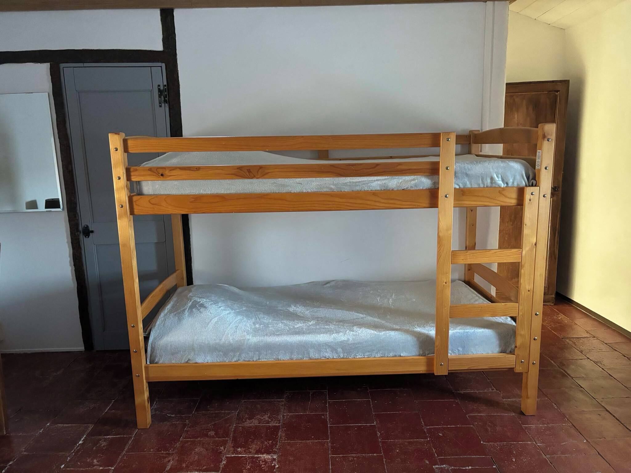 Ein Stockbett mit Holzrahmen und einer Matratze.