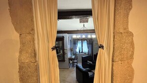 Una puerta con cortinas que da a una sala de estar con chimenea, un sofá y un comedor.