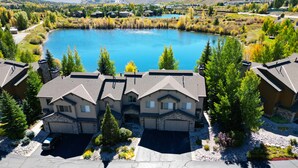 A residential area with houses near a lake, featuring a driveway and a parking area. - Pet Friendly, Spacious Home, Incredible Views, Private Hot tub 152 (Silverthorne)