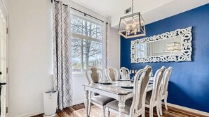 A dining area with a white table and chairs, a blue accent wall, and a large ornate mirror. - Pet Friendly, Spacious Home, Incredible Views, Private Hot tub 152 (Silverthorne)