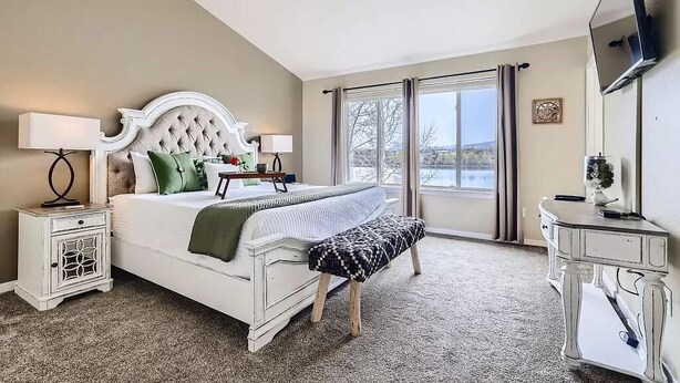 A bedroom with a large bed, a nightstand, a dresser, a television, and a window with curtains. - Pet Friendly, Spacious Home, Incredible Views, Private Hot tub 152 (Silverthorne)