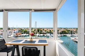 A balcony with a table, chairs, and a vase of flowers. - 396-studio marina's view (Empuriabrava)