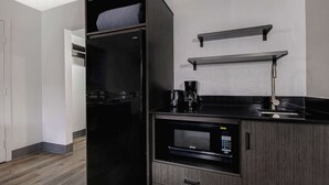 Eine kompakte Küche mit integriertem Kühlschrank, Mikrowelle und Kaffeemaschine.