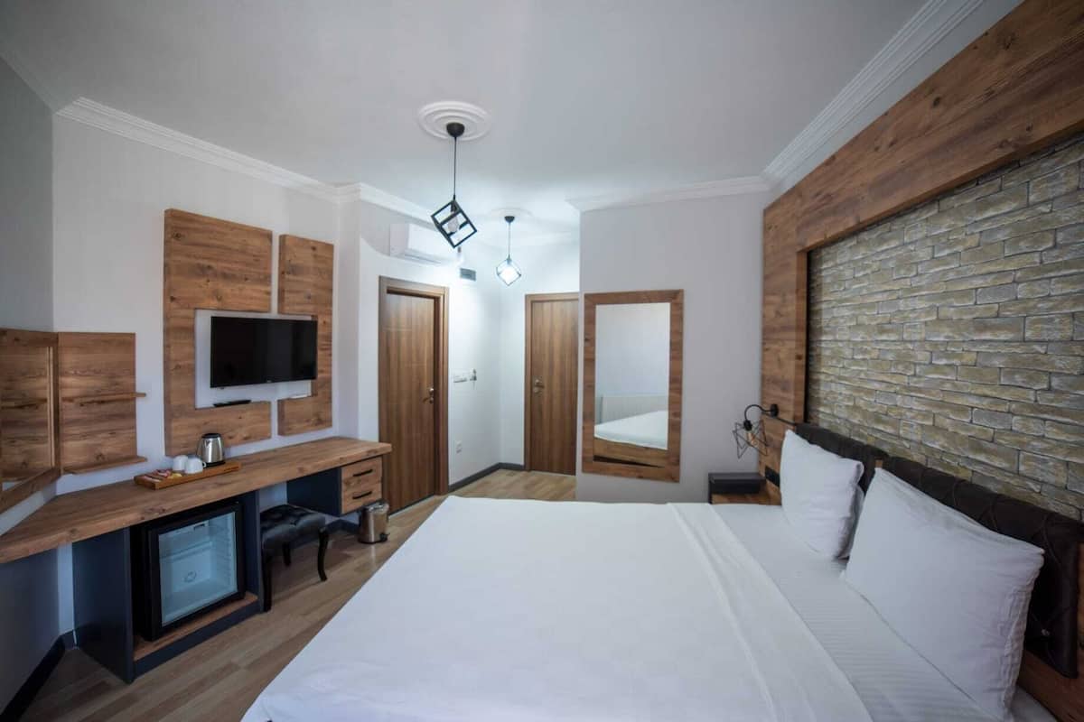 A bedroom with a bed, a TV, a desk, and a wardrobe.