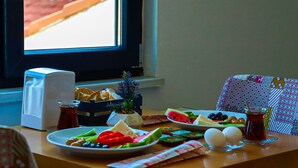 Una mesa de desayuno con platos de comida, un calentador de agua y vistas al exterior.