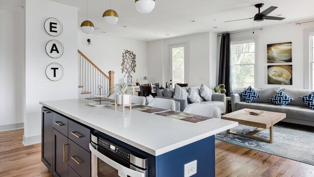 A modern kitchen with a central island, built-in oven, and a dining area with a sofa and coffee table. - Three Story Home With Urban Courtyard Minutes to Downtown (Nashville)