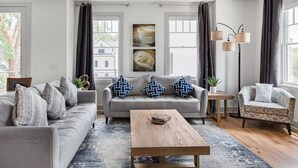 A modern living room with a grey sofa, a wooden coffee table, and a patterned rug. - Three Story Home With Urban Courtyard Minutes to Downtown (Nashville)