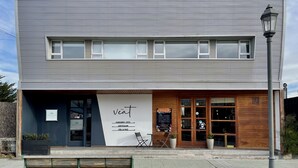 Un bâtiment moderne dont la façade comprend une vitrine avec une enseigne indiquant «The Veat» et une porte d’entrée en bois.