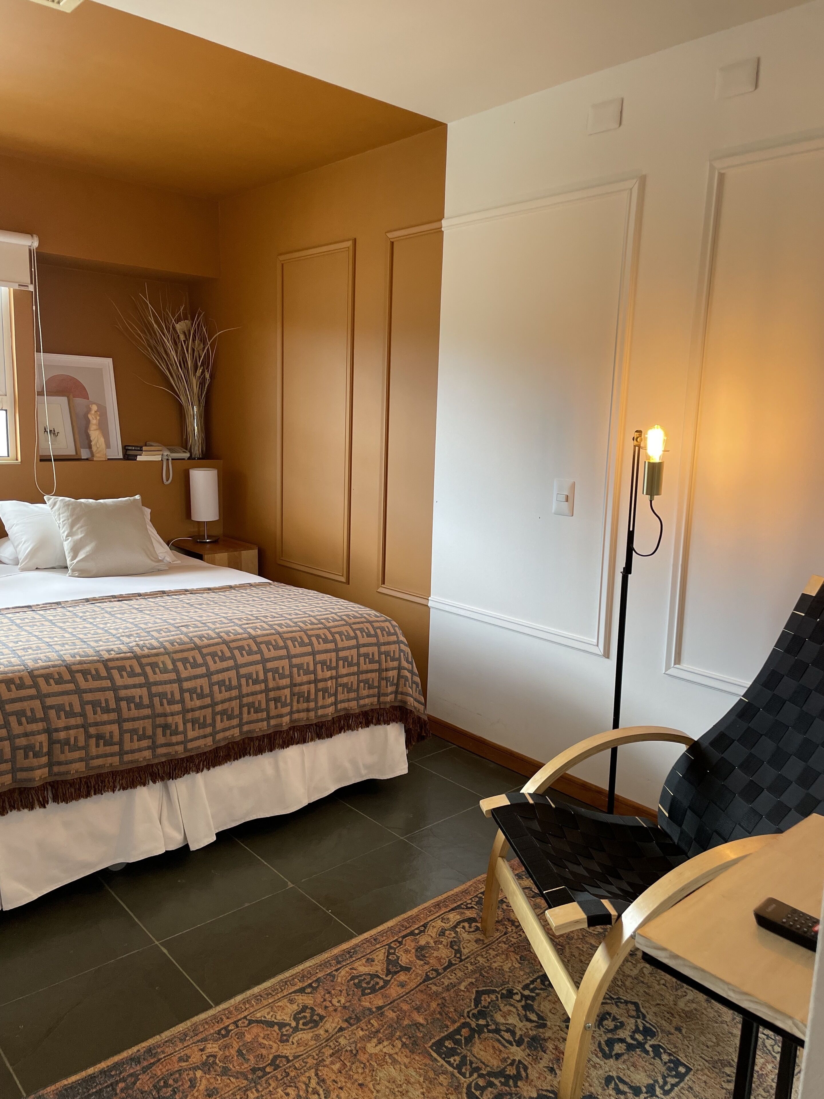 Ein Hotelzimmer mit Bett, Stuhl, Schreibtisch, Lampe und Teppich.