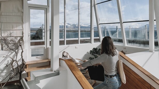 Un intérieur moderne avec de grandes fenêtres donnant sur un lac et des montagnes.