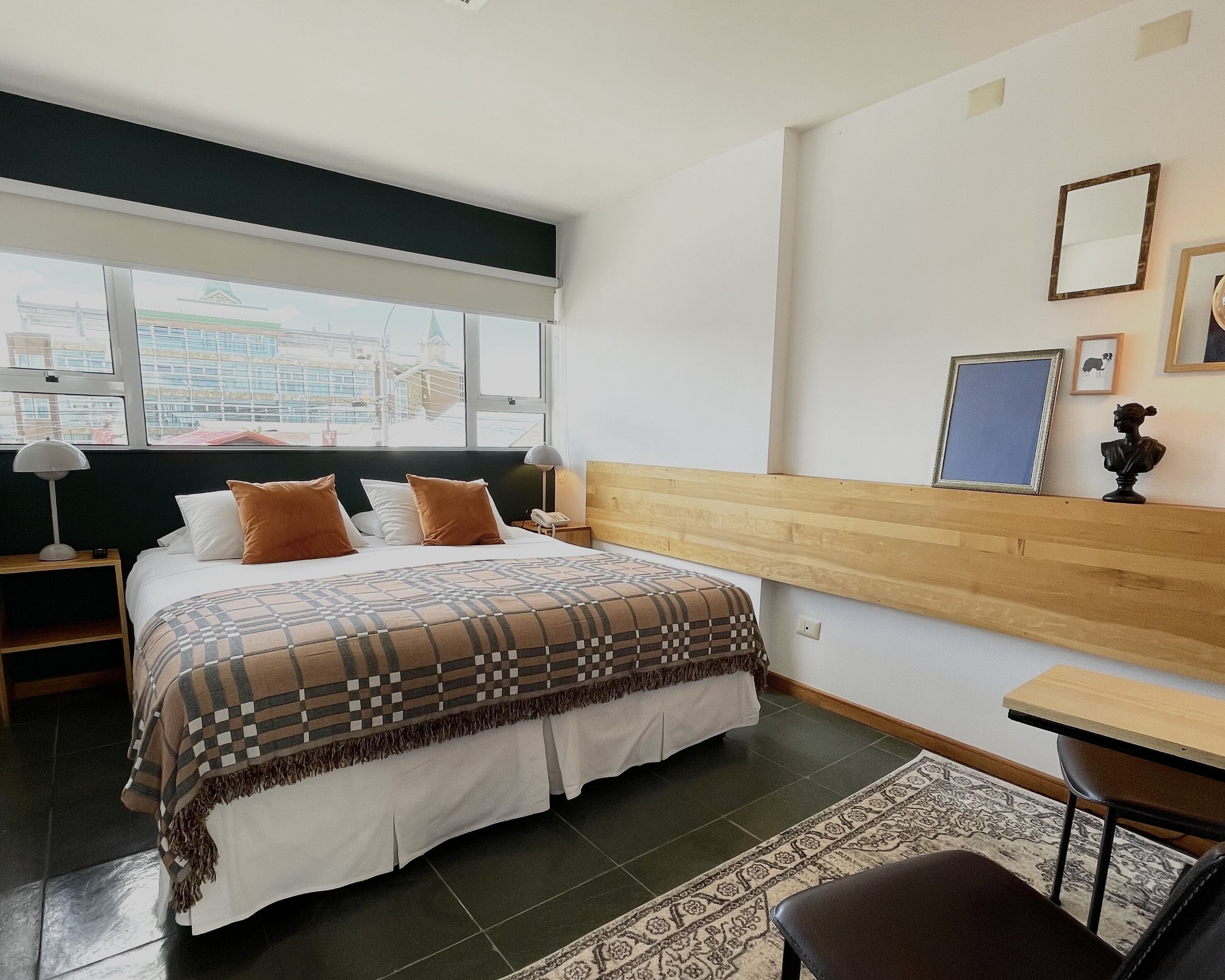 A hotel room with a large bed, a wooden headboard, a desk, and a chair.