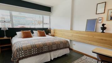 A hotel room with a large bed, a wooden headboard, a desk, and a chair.