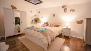 Una camera da letto con un letto, comodini, un armadio, un lucernario e decorazioni a forma di rocce sulle pareti.