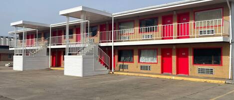 Un motel con edificios de dos pisos, cada uno con una puerta roja y un área exterior cubierta.