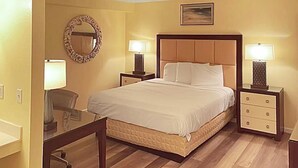 Habitación de hotel con una cama grande, dos mesitas de noche con lámparas, un espejo redondo y un pequeño escritorio con una silla.