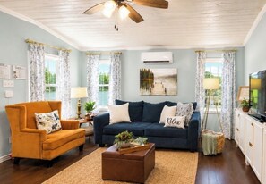 A living room with a sofa, armchair, and coffee table, a ceiling fan, and a painting on the wall. - Lake Sam Rayburn "True" Waterfront Escape - Bring Boat, Kayak & Fishing Poles! (Etoile)