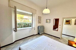 Un dormitorio con cama, ventana con vistas, lámpara colgante y puerta.