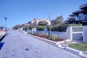 Stroll through a quiet urban neighborhood with neatly trimmed gardens and a residential building with a flat roof.