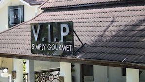 Une enseigne indiquant « V.I.P Simply Gourmet » sur un bâtiment dont le toit est recouvert de tuiles.