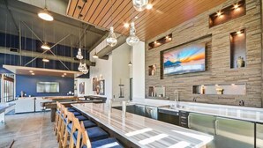 Een moderne keuken met een centraal eiland, een bar en hangende lampen.