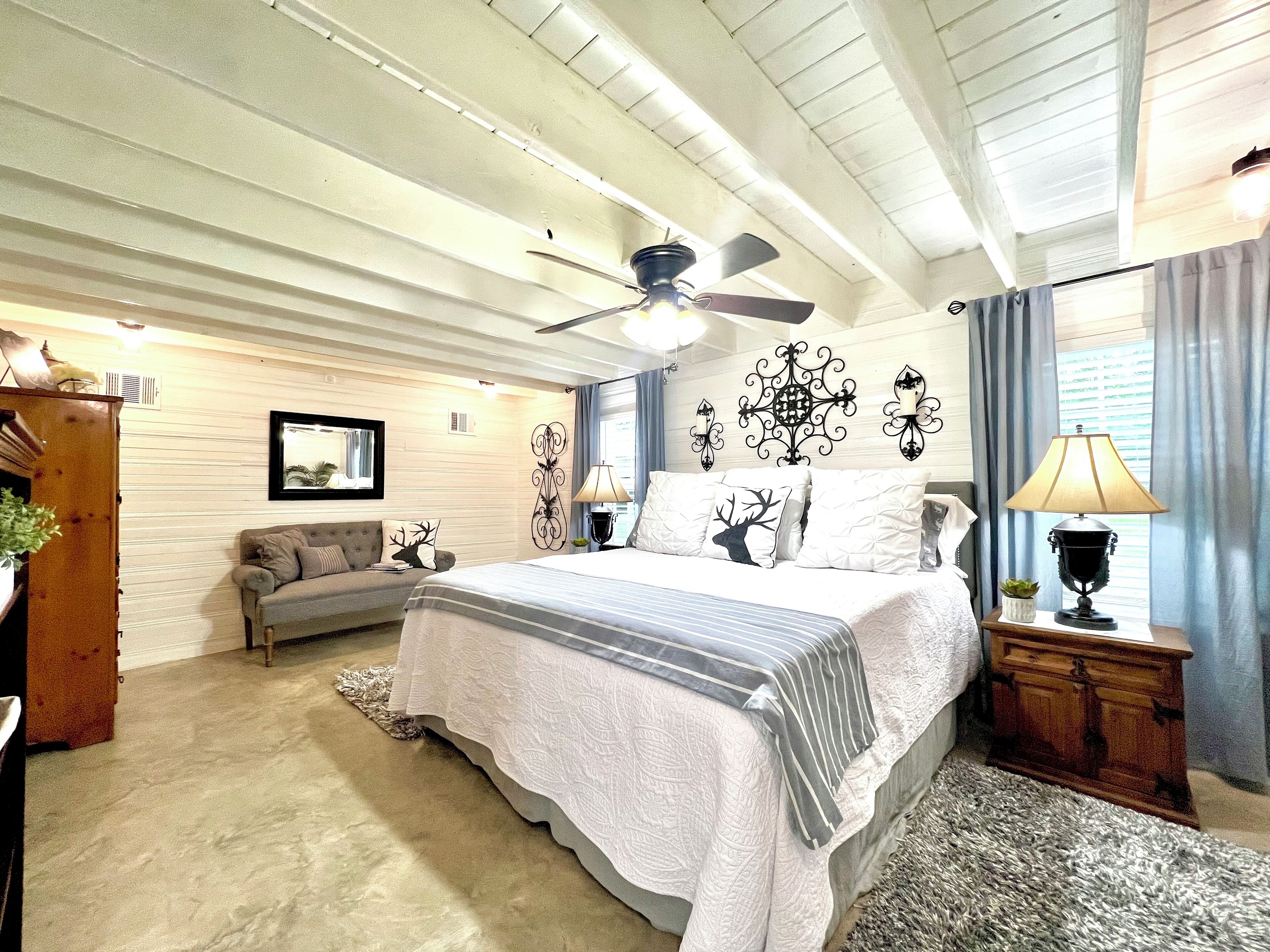A bedroom with a bed, ceiling fan, and a nightstand with a lamp.