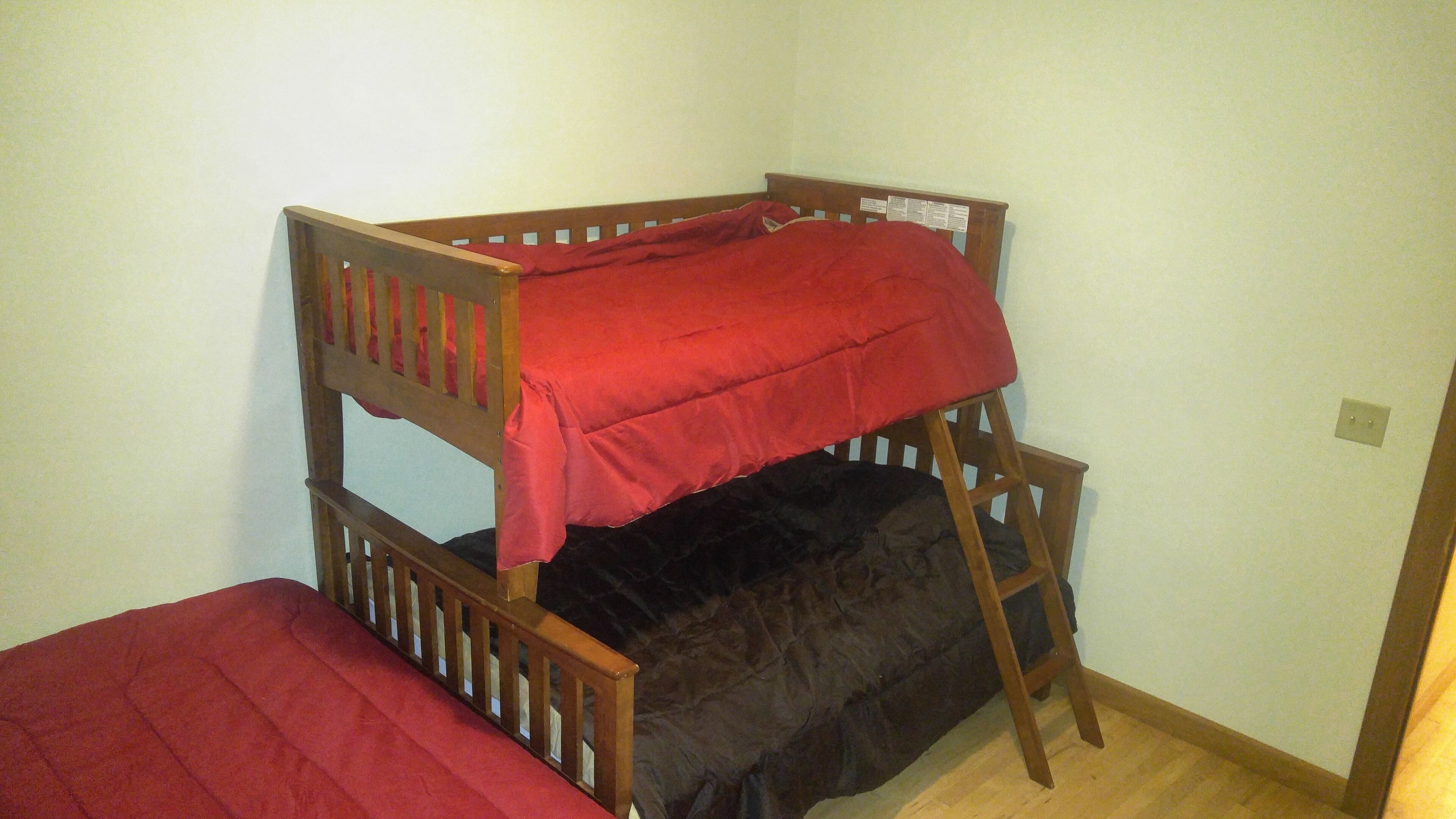 A bunk bed with a red blanket on top and a black blanket on the bottom.