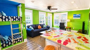 A room with bunk beds, a sofa, a coffee table, and a TV. - Clown Fish Cottage - Pet Friendly with King Bed (Mexico Beach)