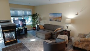 A living room with a fireplace, sofa, armchair, and a television. - Spacious Downtown, First Floor, Patio, sleeps up to 6, Short Walk to Everything! (Traverse City)