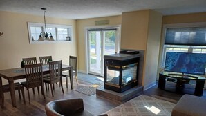 A living room with a fireplace, dining table, and chairs. - Spacious Downtown, First Floor, Patio, sleeps up to 6, Short Walk to Everything! (Traverse City)