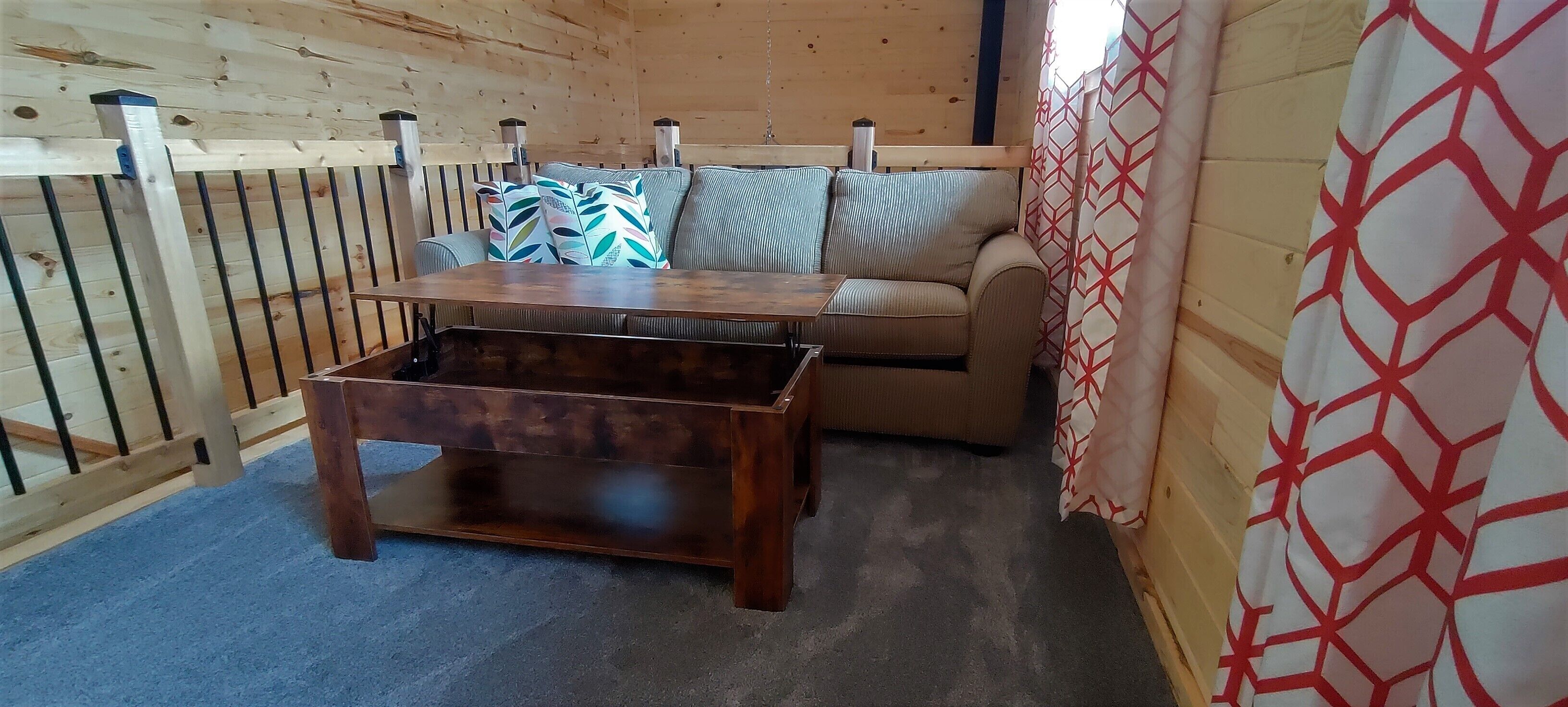 A cozy room with a wooden interior, a sofa with patterned cushions, and a wooden coffee table.