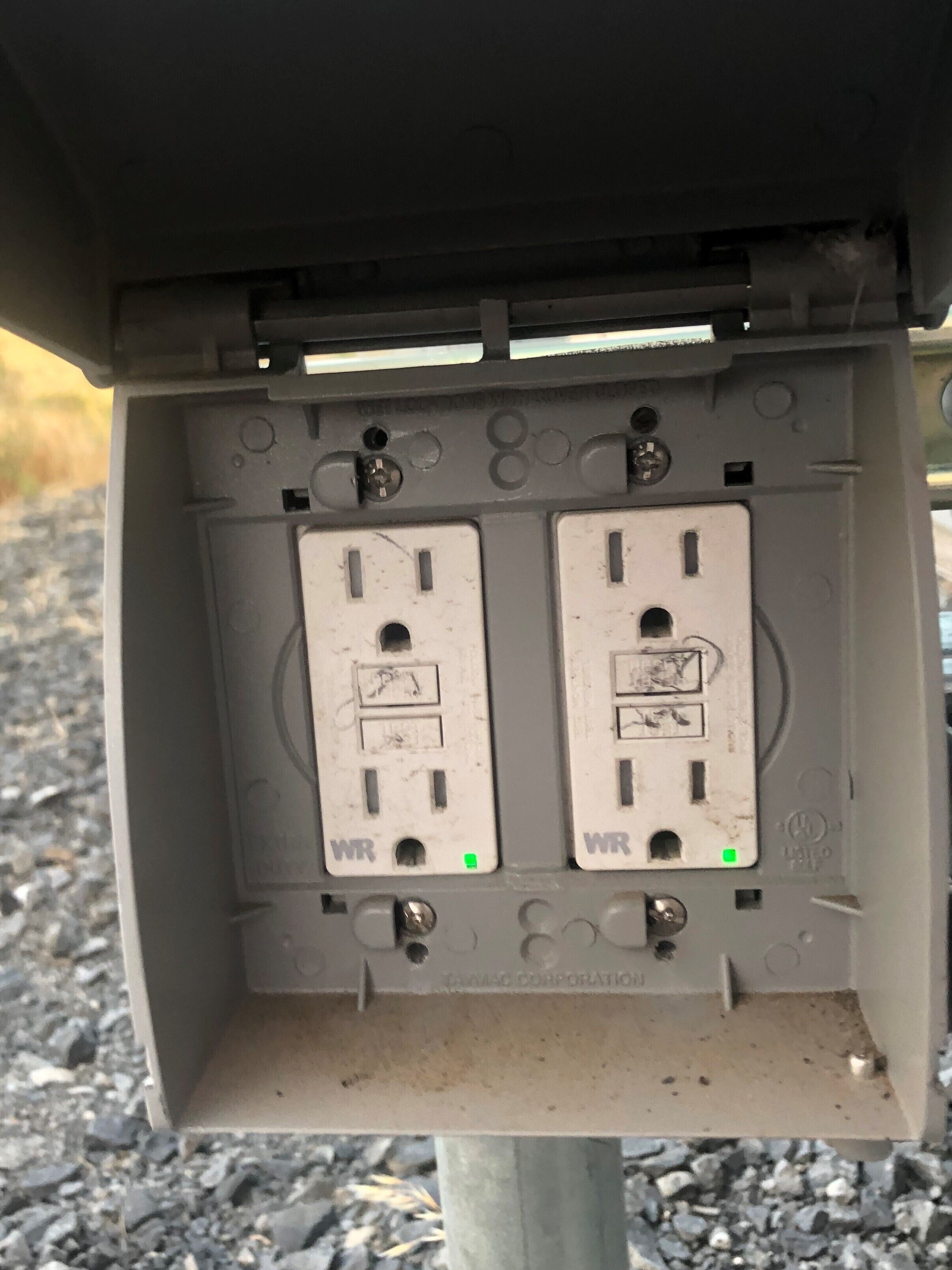A utility box with two white electrical outlets, each marked with 'WR' and a green grounding symbol.