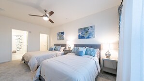 Quarto com duas camas, ventilador de teto e obras de arte nas paredes.