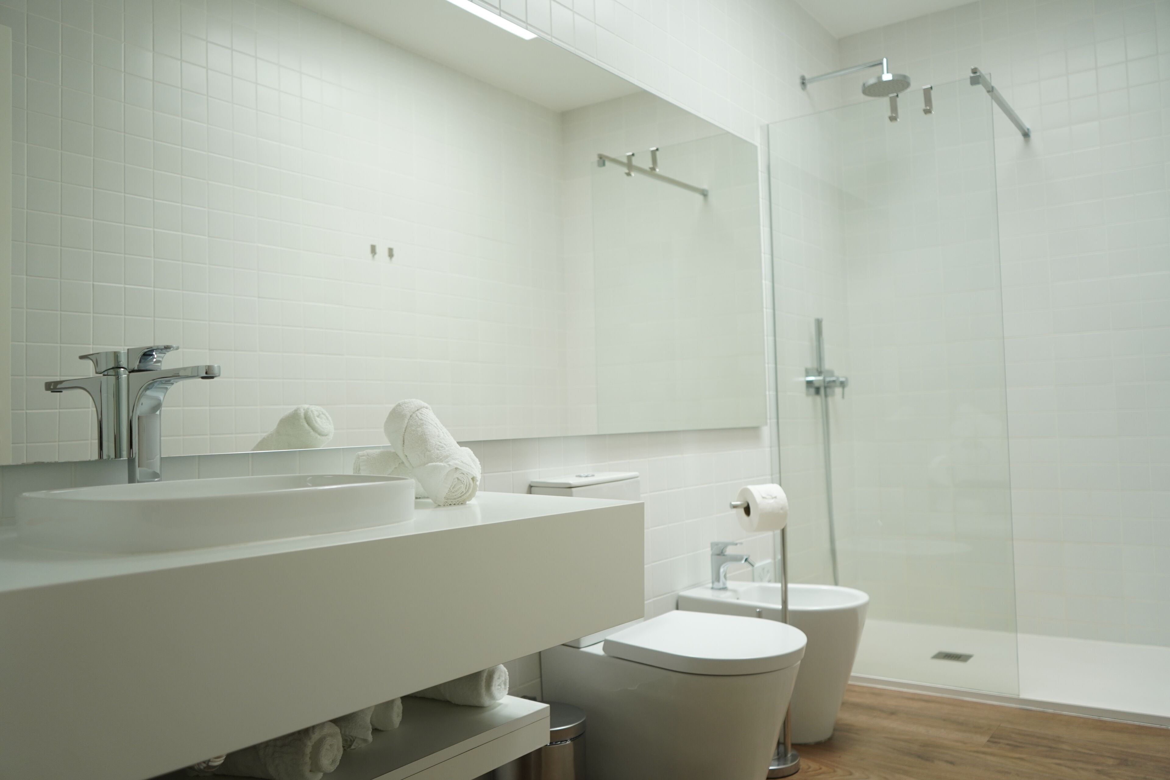 A modern bathroom with a white sink, mirror, and toilet.