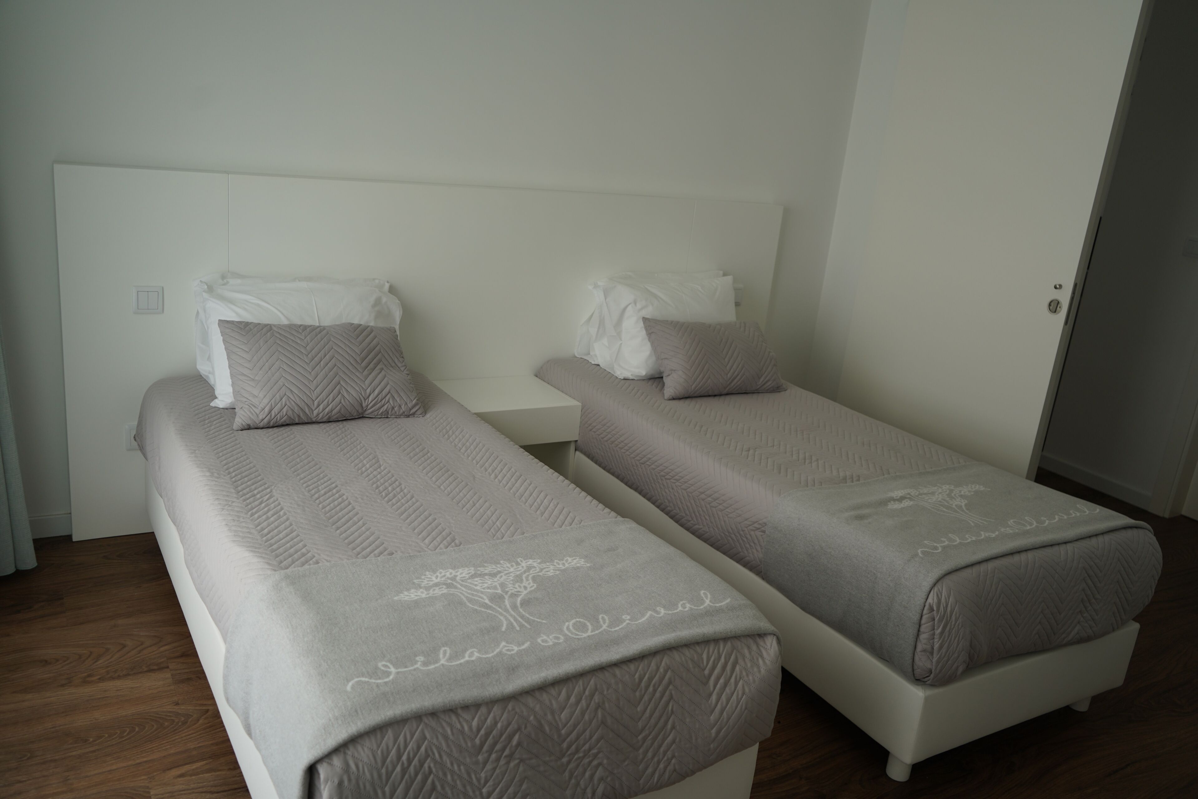 Een hotelkamer met twee eenpersoonsbedden, elk met hoofdeinde en kussens.