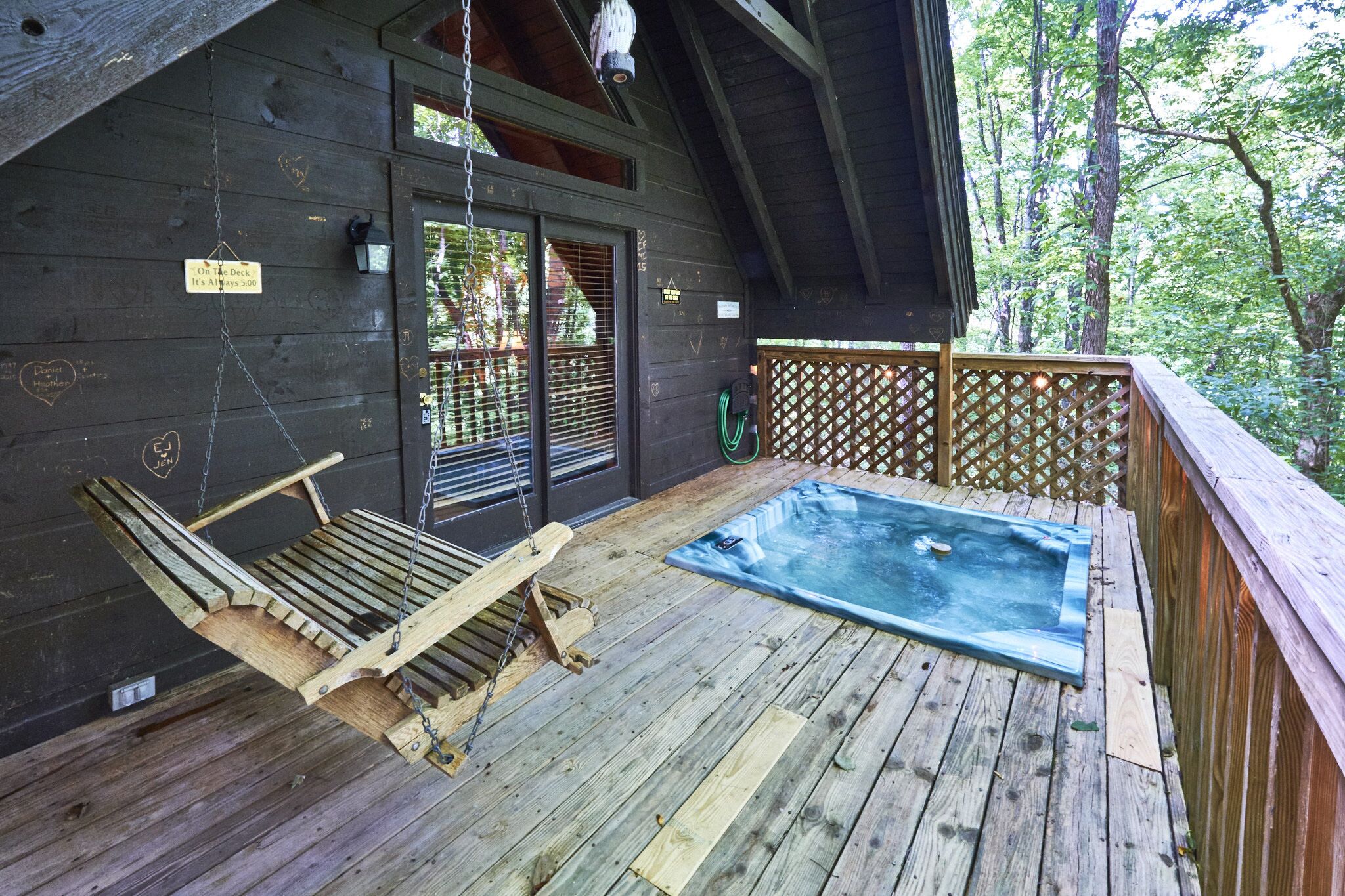 A wooden deck with a hot tub, a swing, and a covered area with a sign indicating a price of $50.
