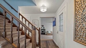 A hallway with a wooden staircase, a decorative wall piece, and a ceiling light fixture.