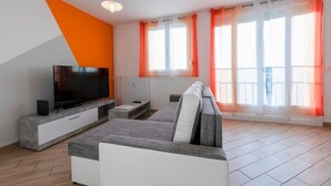 A modern living room with a flat-screen TV, a sofa, and a coffee table. - Appart'Hôtel L'ile en Mouvement (Montbéliard)