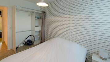 Un dormitorio con cama, armario, mesita de noche y pared con diseño geométrico.