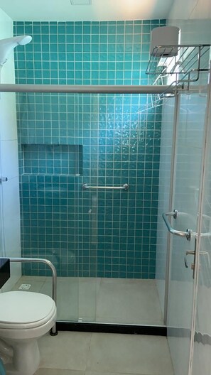 A bathroom with a shower enclosure, a toilet, and a sink.