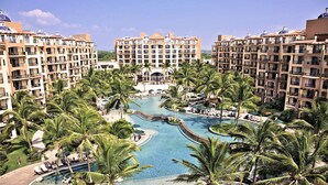 Un complex turístic amb diversos edificis alts, una zona de piscines central envoltada de palmeres i zones d'estar a l'aire lliure.
