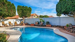 A swimming pool with lounge chairs and potted plants, surrounded by a white wall and trees. - 1st Part of Description has Discounts! Best part of Scottsdale! Pool & Hot Tub! (Scottsdale)