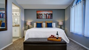 A hotel room with a bed, bedside lamps, a painting, a tray with a bottle and glass, and a view of the bathroom. - 1st Part of Description has Discounts! Best part of Scottsdale! Pool & Hot Tub! (Scottsdale)