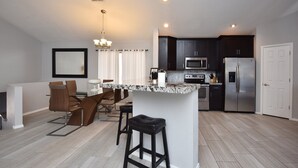 A modern kitchen with dark cabinets, a stainless steel refrigerator, and a marble countertop island. - 1st Part of Description has Discounts! Best part of Scottsdale! Pool & Hot Tub! (Scottsdale)