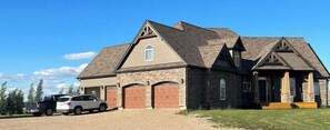 Stunning two-story home with a central entrance and garage doors, set amidst a beautifully manicured lawn.
