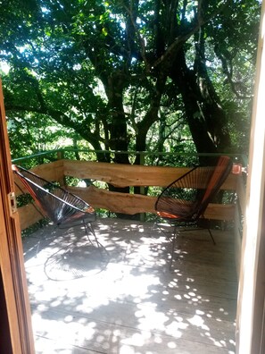 A wooden deck with two metal chairs and a hammock. - The Green Tree Lodge (Monteverde)