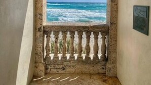 Une porte en arc donnant sur un balcon avec vue sur la mer.